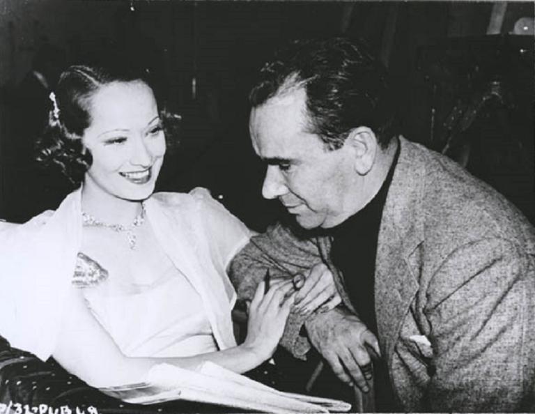 Merle Oberon linking arms with William K Howard.