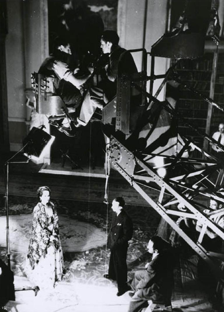 Overhead production shot of Merle Oberon acting with a movie camera on a crane above her