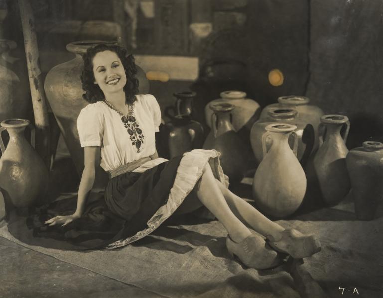 Betty Bryant on the set of Forty Thousand Horsemen wearing a peasant dress and reclining among earthenware pots.