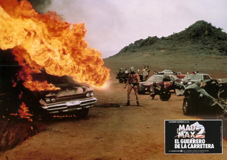 Mad Max 2 lobby card showing Humungus (Kjell Nilsson) next to a burning car.