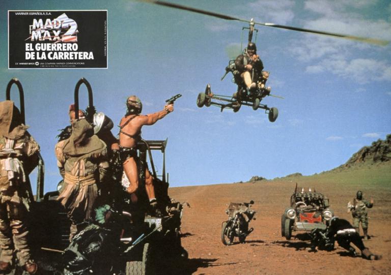 Mad Max 2 lobby card shows Humungus (Kjell Nilsson) shooting at the Gyro Captain (Bruce Spence) as he flies overhead.