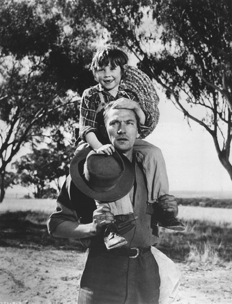Peter Finch with Dana Wilson on his shoulders holding his hat on a country road