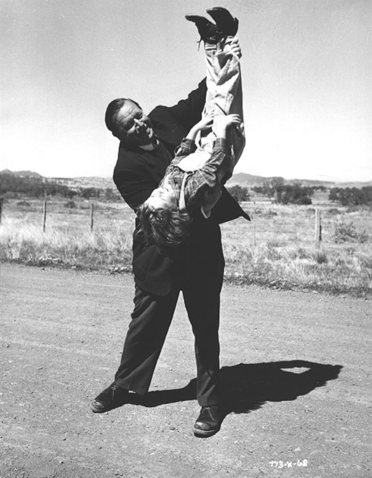 The Shiralee director, Leslie Norman, holding Dana Wilson (Buster) upside down