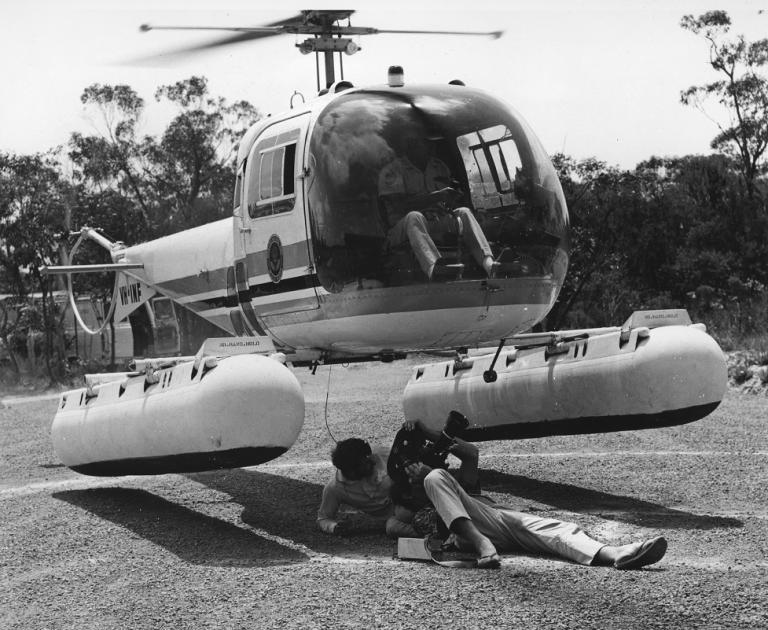 Camera crew filming underneath a helicopter as it takes off.