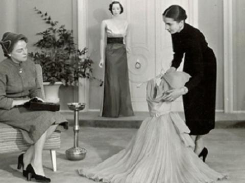 A woman is showing another woman a dress in a fashion store.