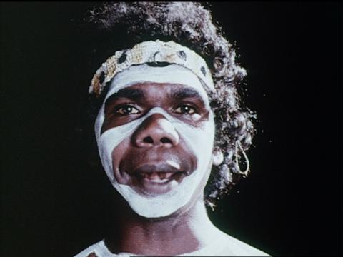 A young David Gulpilil looking directly at the camera with white paint on his face
