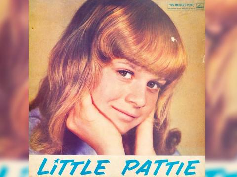 Close up of a teenage girl with blonde hair, resting her chin in her hands and looking at camera with a slight smile. At the bottom it says LITTLE PATTIE