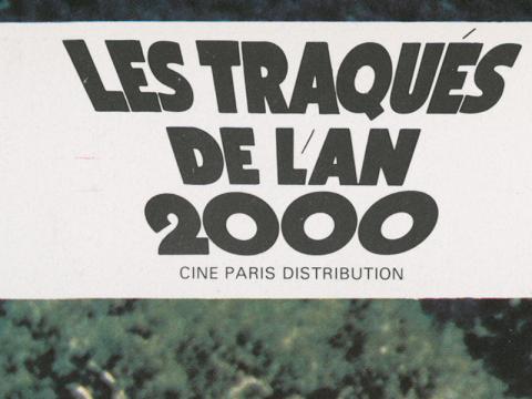 Part of a lobby card image with black block writing that says in French 'Les Tragues de l'an 2000' which translates to 'The Hunted People of the Year 2000' which was the French title for the film 'Turkey Shoot'