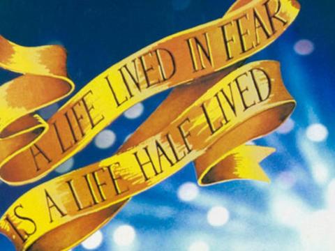 Cropped section of a Strictly Ballroom film poster that shows a gold ribbon against a blue background. On the ribbon are the words "A life lived in fear is a life half lived"