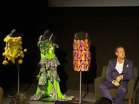 Tim Chappel is interviewed on stage at the NFSA with three Priscilla film costumes on mannequins behind him
