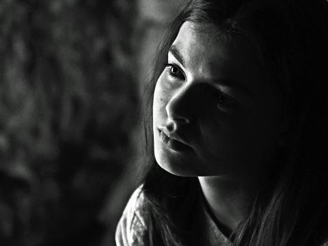 Close up of young woman with head tilted to the side staring at a point off camera. Still from the film Brolga.