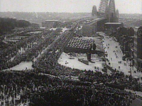 Black and white image of some of the crowds at the opening of the Sydney Harbour Bridge. A sea of people line the roadways ready for the procession.