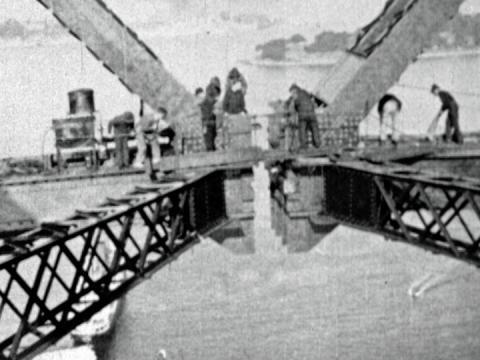 Black and white image of the two arches of the Sydney Harbour Bridge almost coming together to meet in 1930.