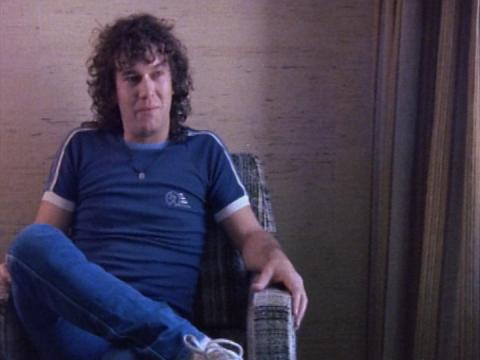Jimmy Barnes sitting in an armchair wearing denim jeans and a blue t-shirt.