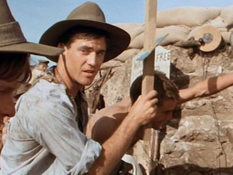 Mel Gibson as Frank looks over at Archy (Mark Lee). They are in the trenches and wear digger's hats.