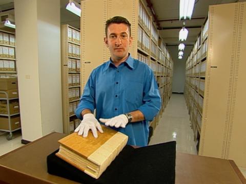 Warren Brown stands in an archival storage vault with Cook's Endeavour journal.