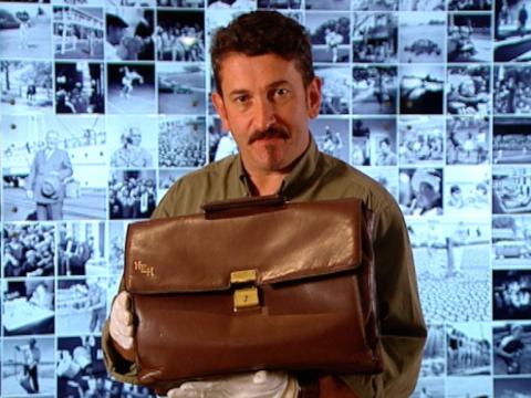 Warren Brown holding a brown leather briefcase.
