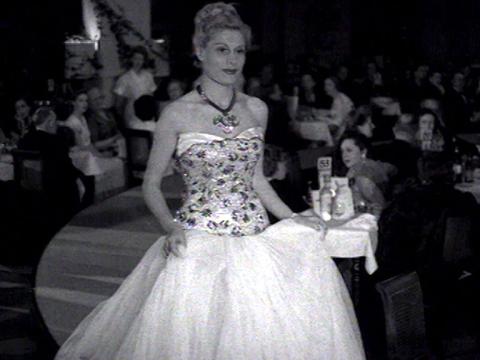 A woman is wearing an evening gown in a fashion parade.