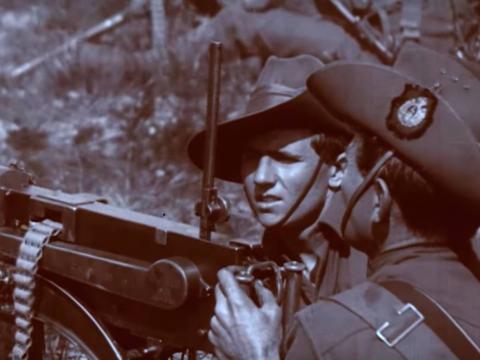 Two Anzac soldiers fire a machine gun on a First World War battlefield