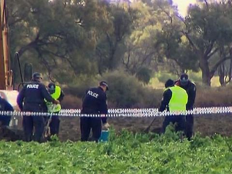 A group of police office in a taped off agricultural area in rural NSW search for remains of a body. Next to them is a large earth mover.