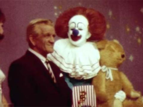 Bobo the clown on set with a man and a large teddy bear