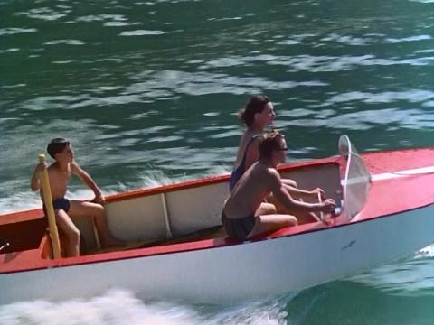 Three young kids speeding on a boat
