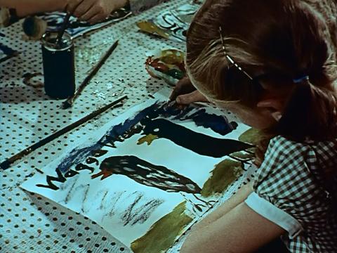 A young girl at school, working on a drawing featuring two crows, and the words Wagga Wagga