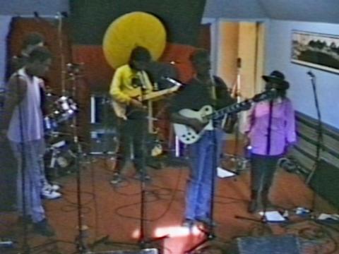 Archie Roach, Ruby Hunter and their band in a radio studio performing a song. 