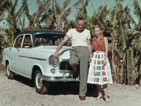 A young couple stands in front of their Holden Car