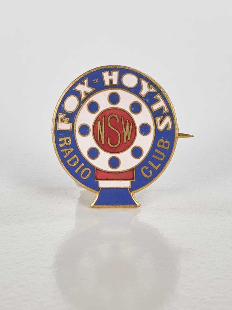 An enamel and metal badge with the words Fox Hoyts printed on it. 