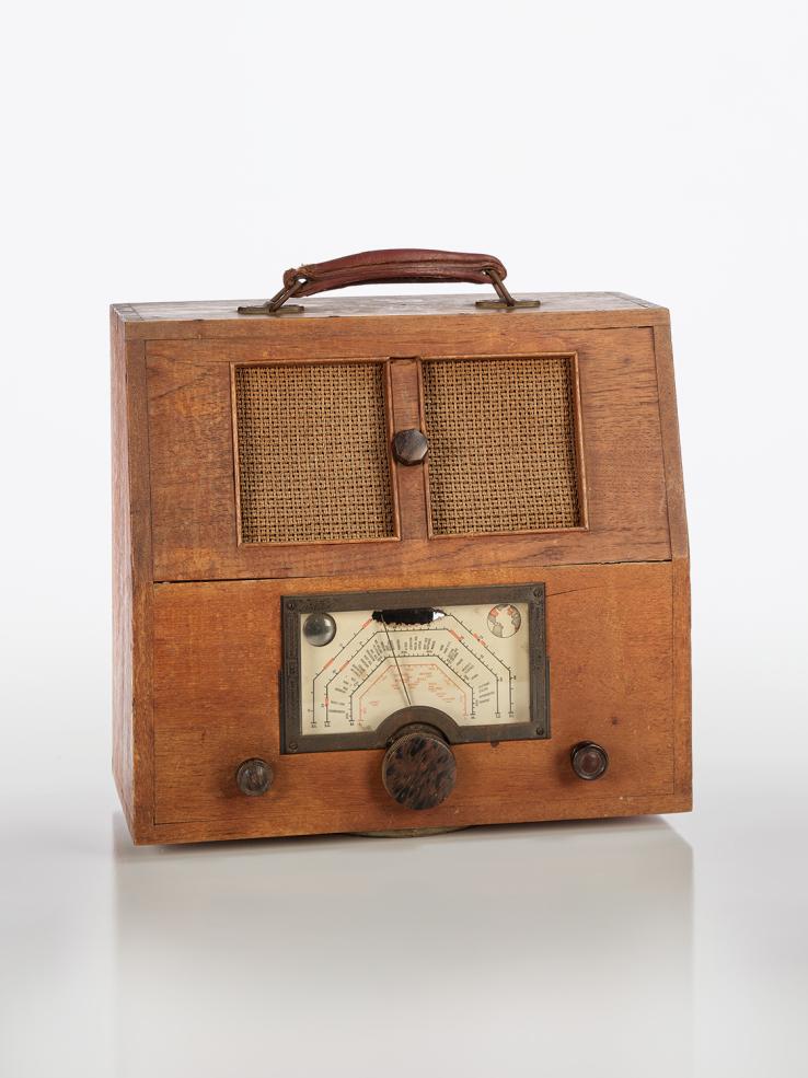 A homemade radio with a dial and speakers on the front and a handle on top. C1936