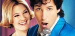 Close up of a young woman with short blonde hair (Drew Barrymore) smiling and looking at a man (Adam Sandler) singing into a microphone in a promotional shot for the film The Wedding Singer. 