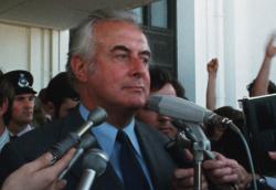 Gough Whitlam on the steps of Parliament House speaking into media microphones.