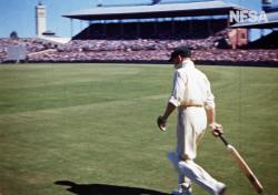 Side-on view of Donald Bradman walking onto the Sydney Cricket Ground in 1949.