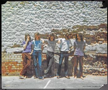 The five members of the band Cold Chisel standing in front of a brick wall. Text at bottom reads 'Cold Chisel - October 1973'.