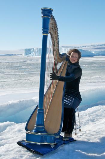 Photo of Alice Giles at Mawson Station, Antarctica playing a harp on the ice