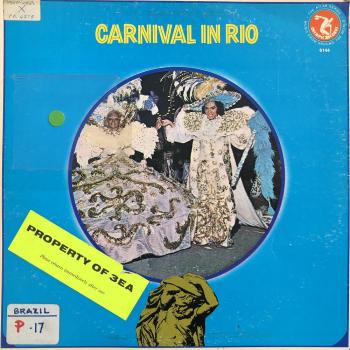 Blue record cover with central image of a man and woman dressed in outrageous carnival costumes