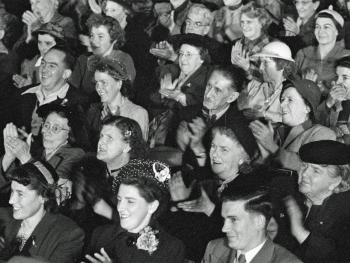 Group of people in a studio audience smiling and clapping