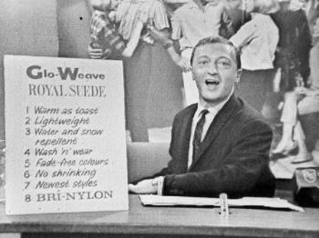 Still television image of Graham Kennedy holding an advertisement for Glo-Weave.