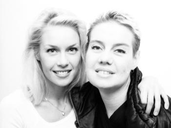 Black and white head and shoulders shot of two young women looking directly at camera.
