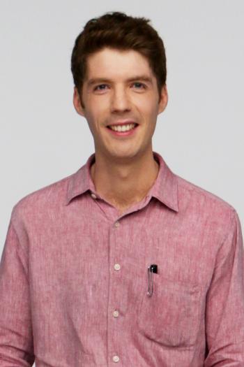 A portrait of a man in a collared shirt. He has a pen in his pocket.