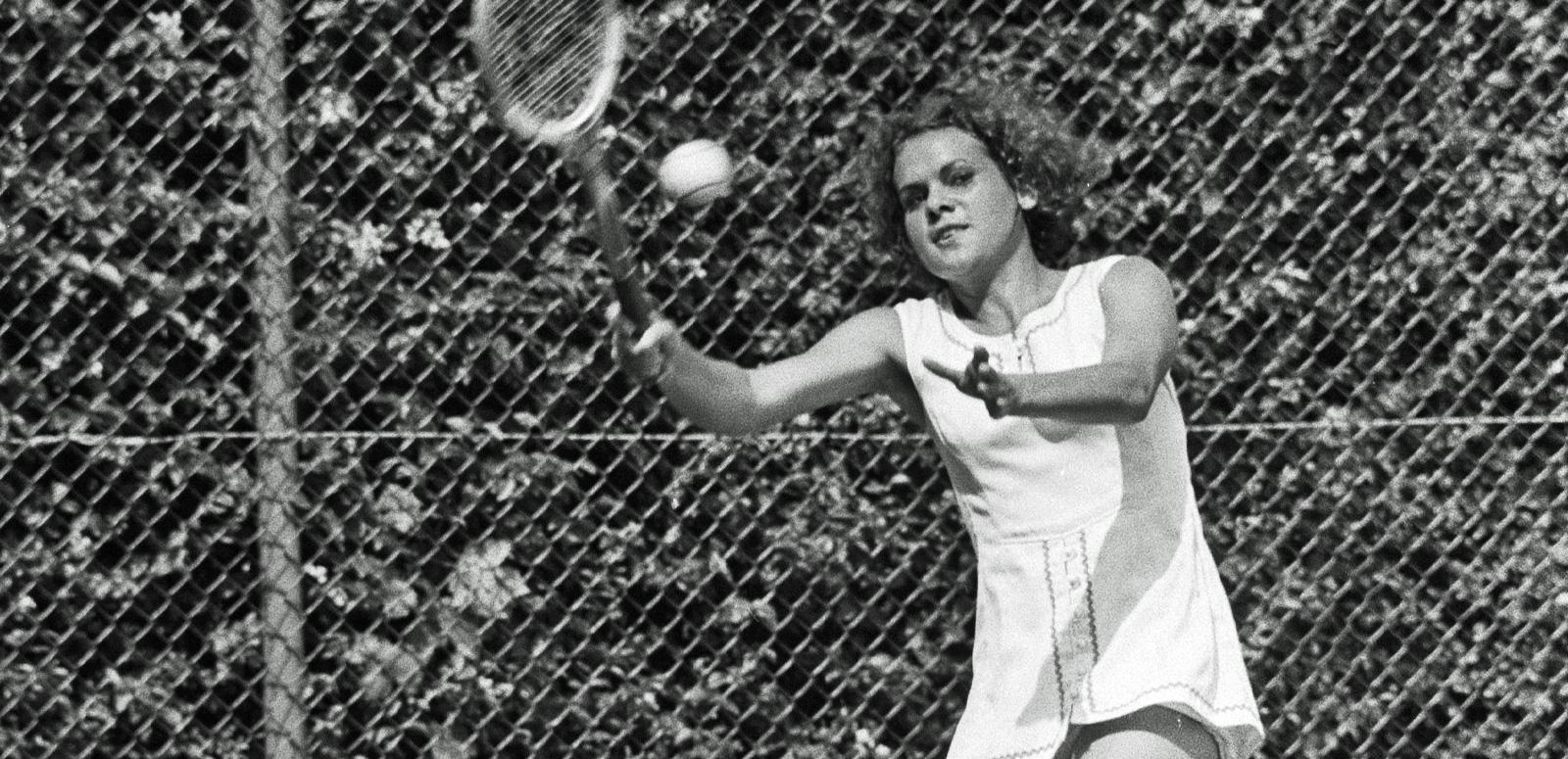 Evonne Goolagong-Cawley holding a wooden tennis racket and about to hit a tennis ball.