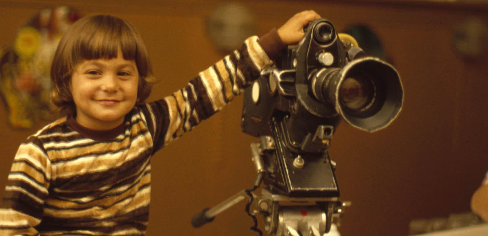 A young boy holds a camera in the 1960s