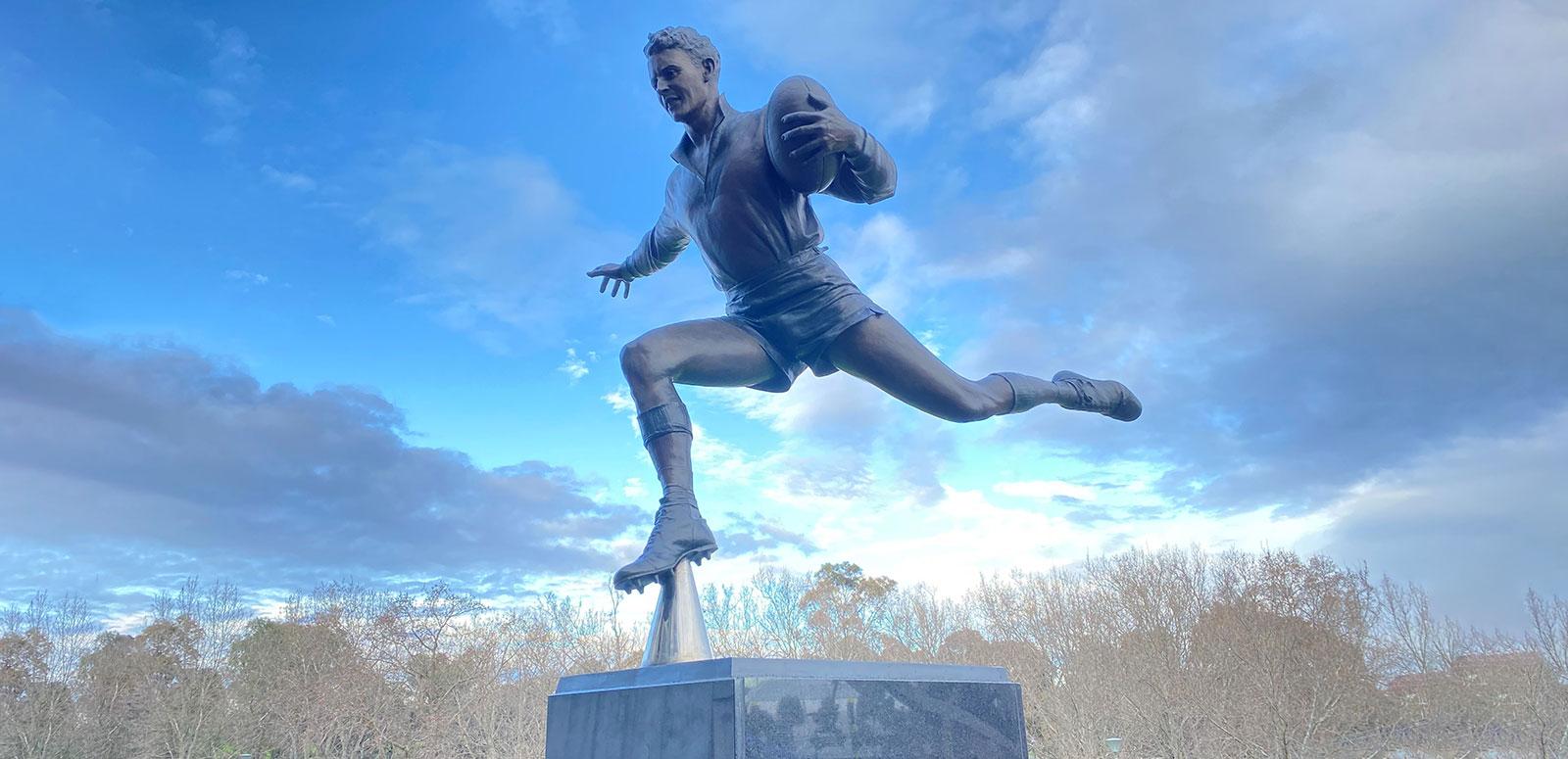 Statue of a man playing Aussie Rules football.