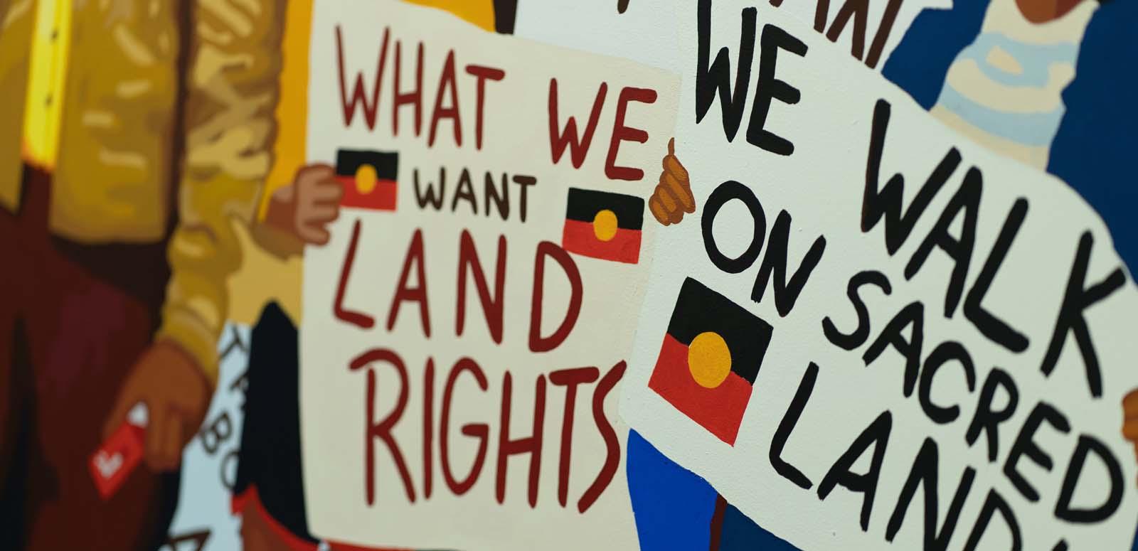 Protesters hold banners calling for Aboriginal land rights at a march