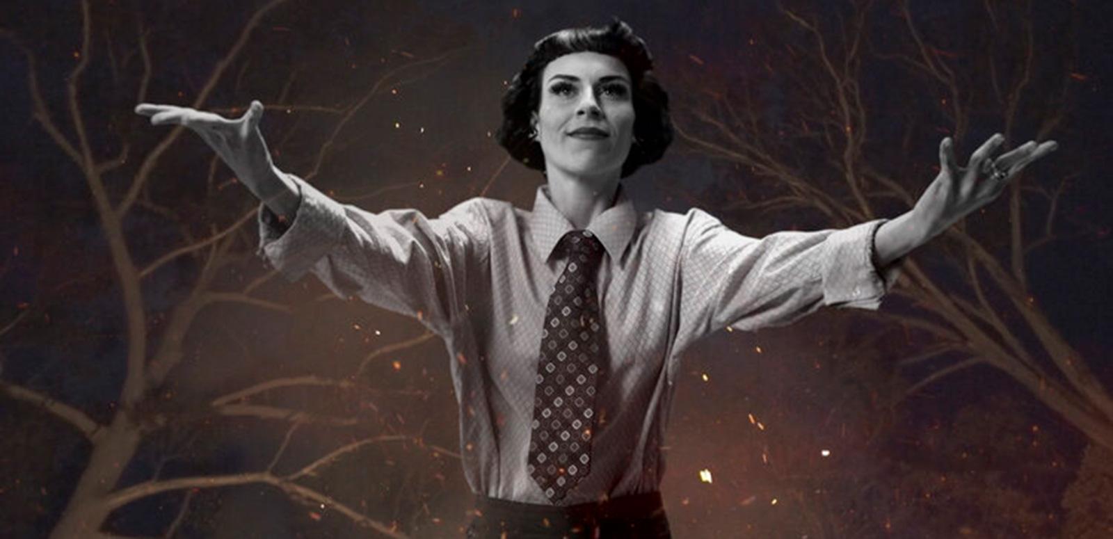 A young woman with short dark hair wearing a business shirt and tie with her arms stretched out wide in front of her. Behind her in the night sky there are tree branches, stars and flickering flames