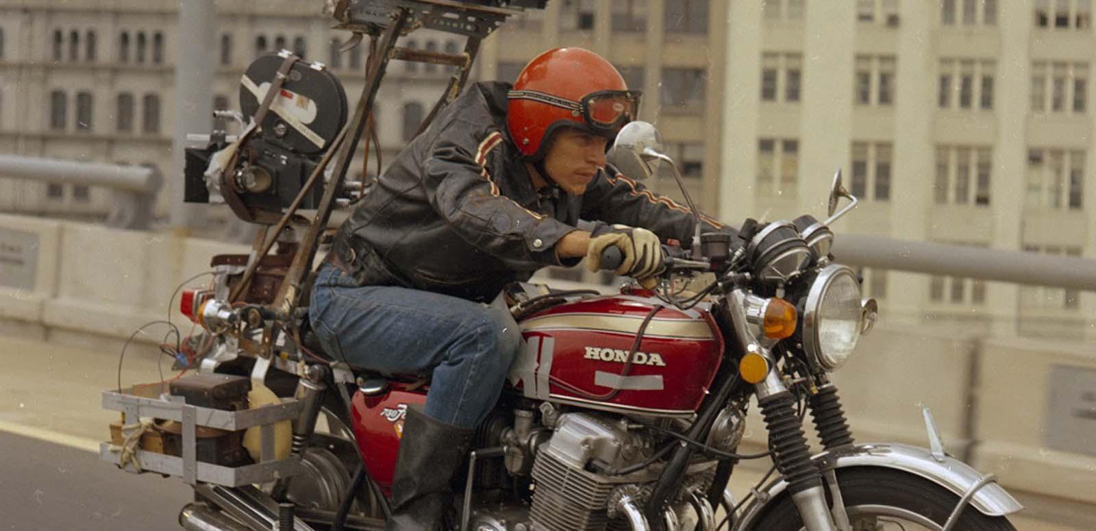 A man rides a motorcycle with a camera mounted on the back.