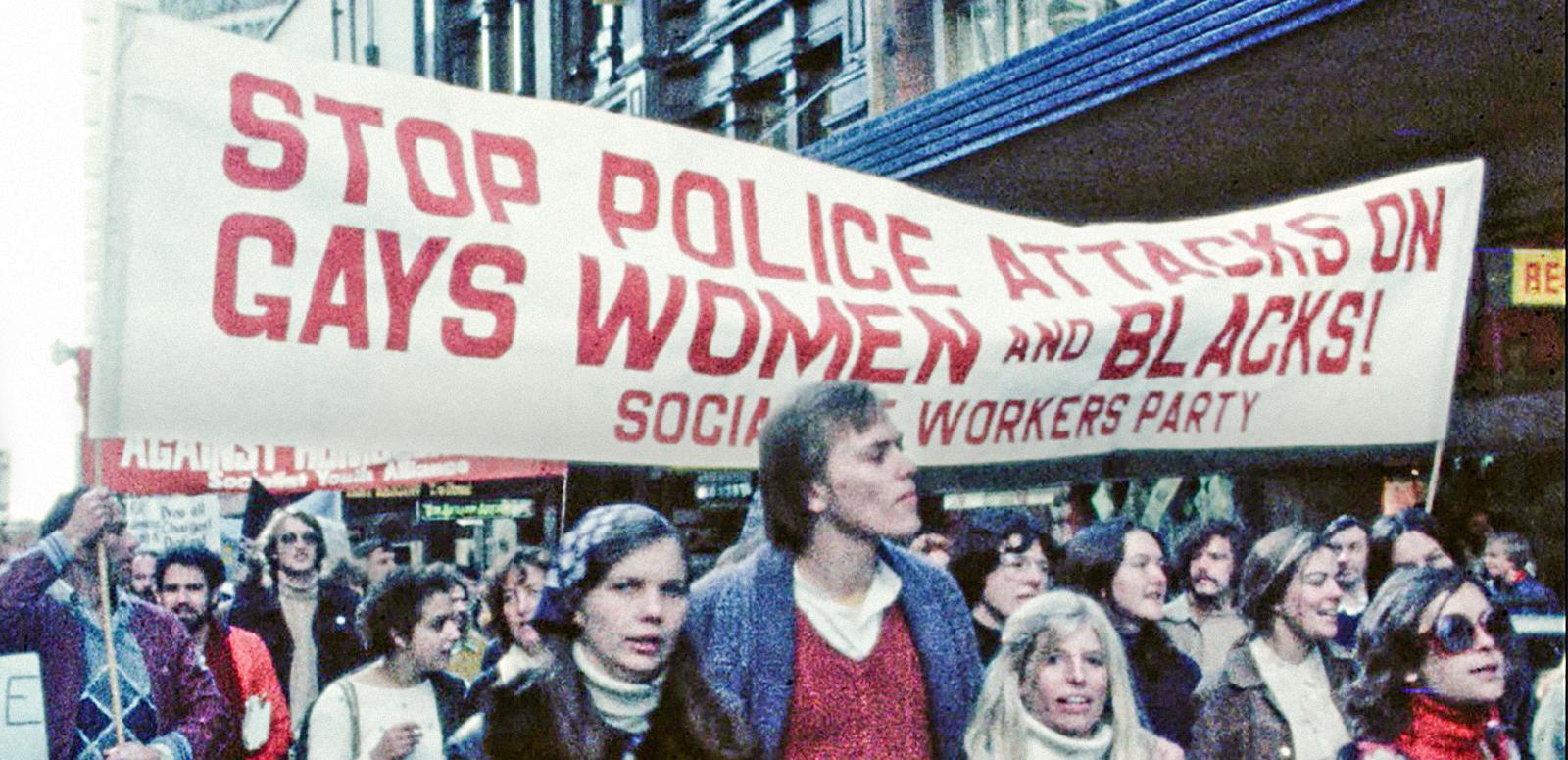 A Sydney protest march in the late 1970s with young people walking under a banner that reads 'Stop police attacks on gays, women and blacks!'