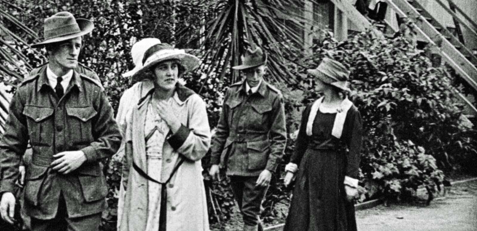 Two Australian soldiers from the First World War walk in uniform, accompanied by three women