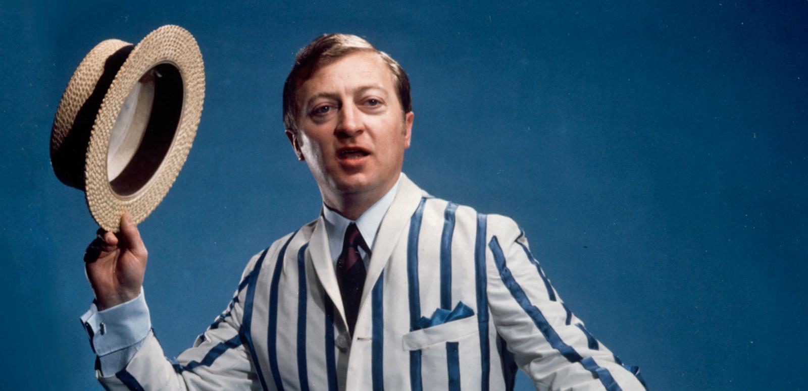 Graham Kennedy wearing a striped jacket and holding a straw boater hat in a promo shot for GTV 9.